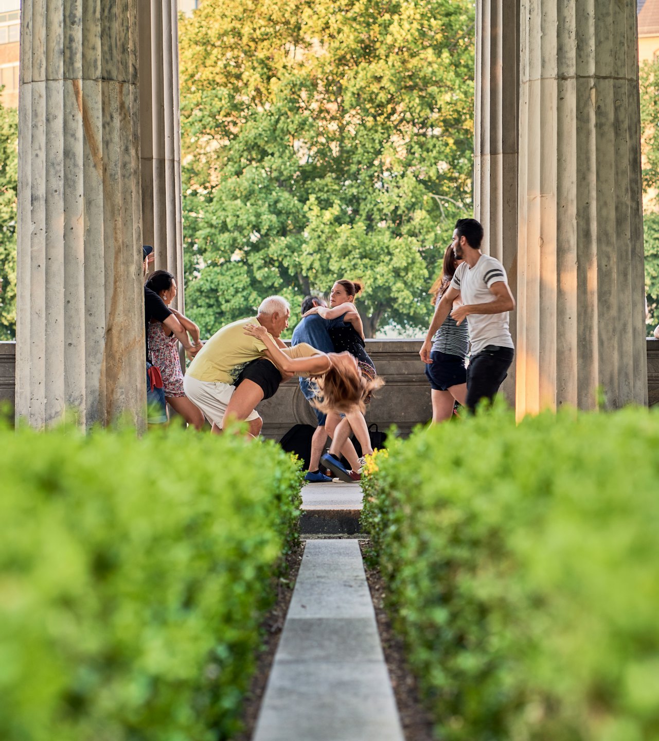 Un groupe diversifié de personnes danse en plein air près d'arbres.